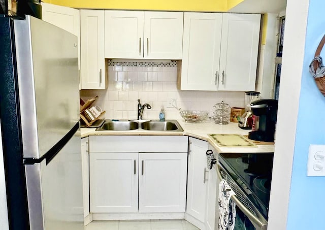 kitchen with range with electric stovetop, white cabinetry, sink, and stainless steel refrigerator