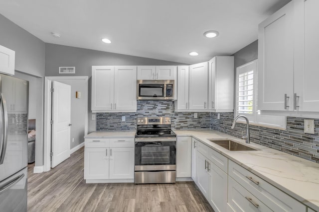 25081 Overseas Hwy, Summerland, FL 33042 - kitchen with stainless steel appliances, a sink, vaulted ceiling, white cabinetry, and backsplash