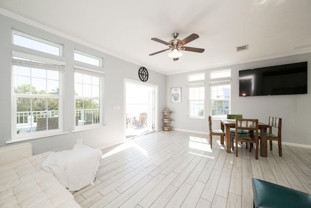 living area with light wood-style flooring, visible vents, baseboards, and ornamental molding