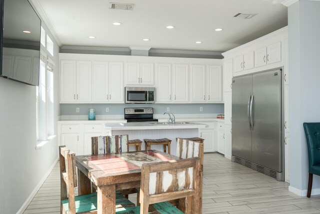 kitchen featuring visible vents, ornamental molding, stainless steel appliances, light countertops, and a sink