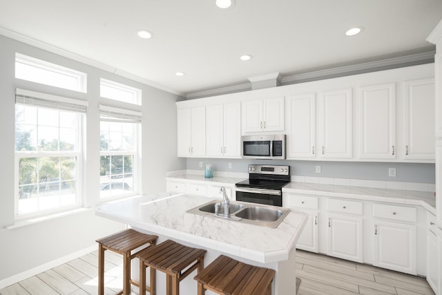 kitchen with a breakfast bar area, stainless steel appliances, ornamental molding, white cabinetry, and a sink