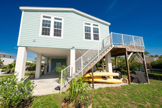 rear view of house with stairs, a carport, and a patio area