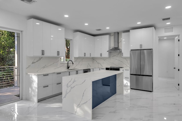 kitchen with sink, stainless steel fridge, white cabinetry, a center island, and wall chimney exhaust hood