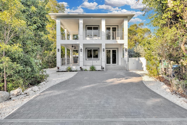 view of front of home with ceiling fan, a balcony, and french doors