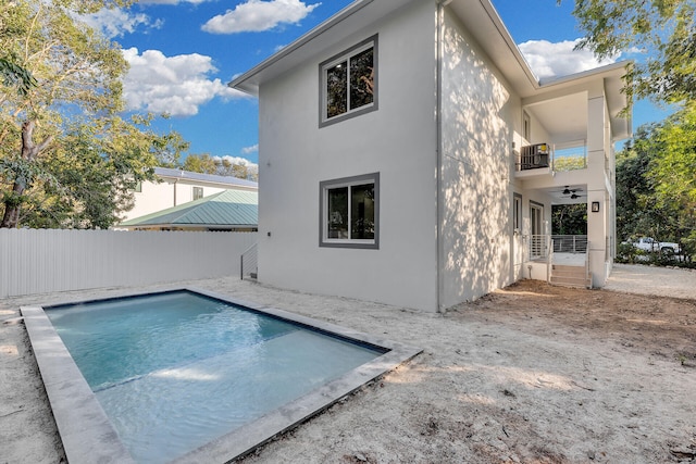 back of house featuring a fenced in pool, a balcony, and ceiling fan