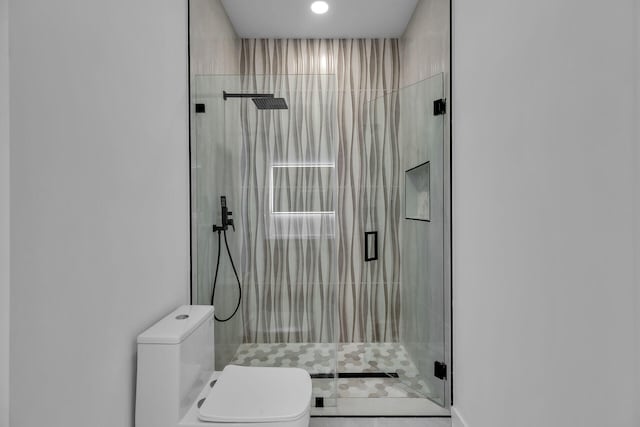 bathroom featuring a shower with shower door and toilet