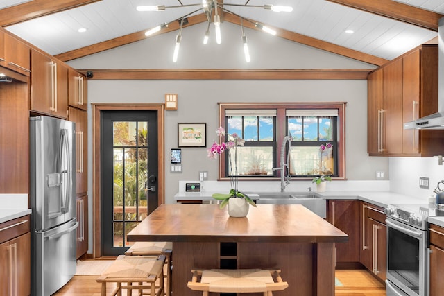 kitchen with sink, vaulted ceiling with beams, stainless steel appliances, a kitchen breakfast bar, and a kitchen island