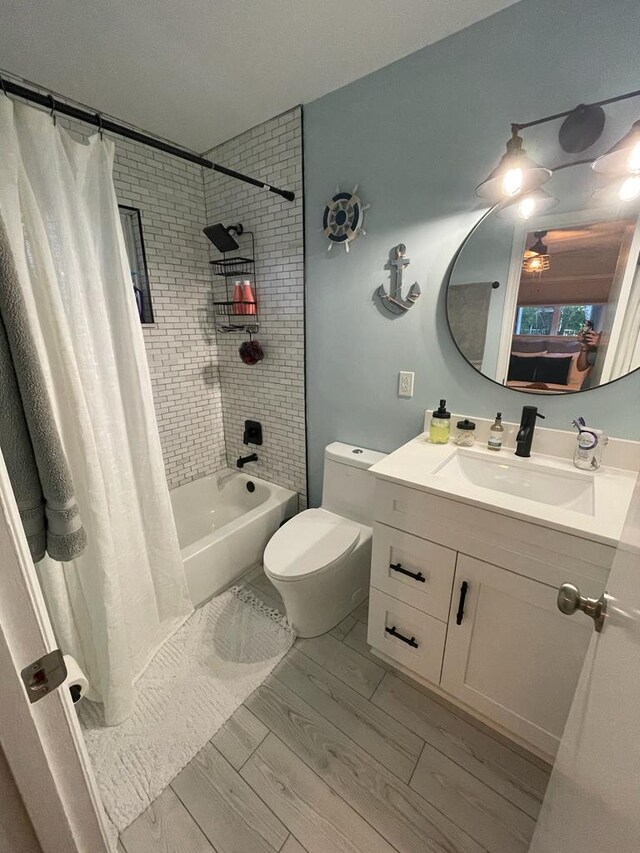 full bathroom with vanity, hardwood / wood-style floors, shower / bathtub combination with curtain, and toilet