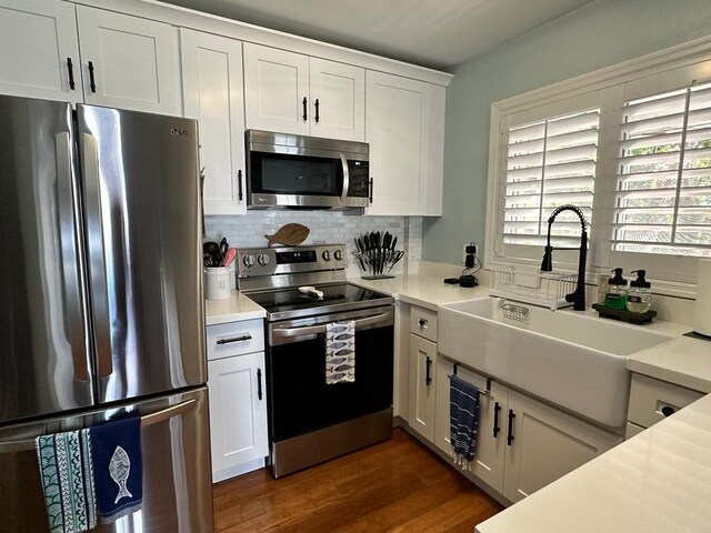 kitchen with stainless steel appliances, white cabinetry, sink, and backsplash