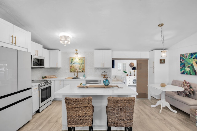 kitchen with a kitchen island, decorative light fixtures, sink, white cabinets, and stainless steel appliances