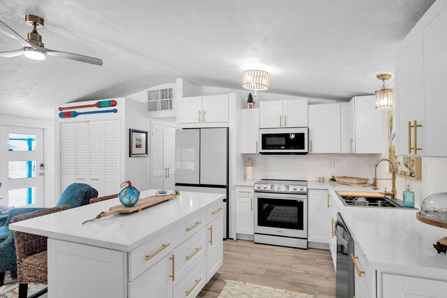 kitchen featuring white appliances, sink, a kitchen island, and white cabinets