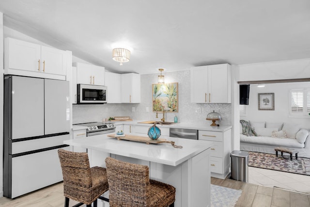 kitchen featuring stainless steel appliances, light countertops, light wood-style floors, white cabinets, and a sink