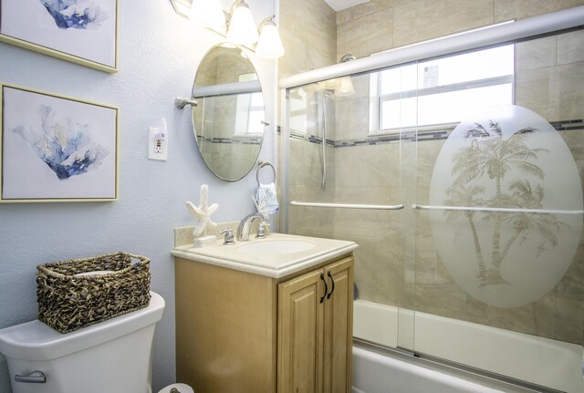 full bathroom featuring vanity, bath / shower combo with glass door, and toilet