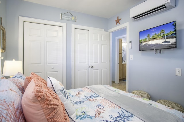 bedroom with a wall mounted AC and two closets