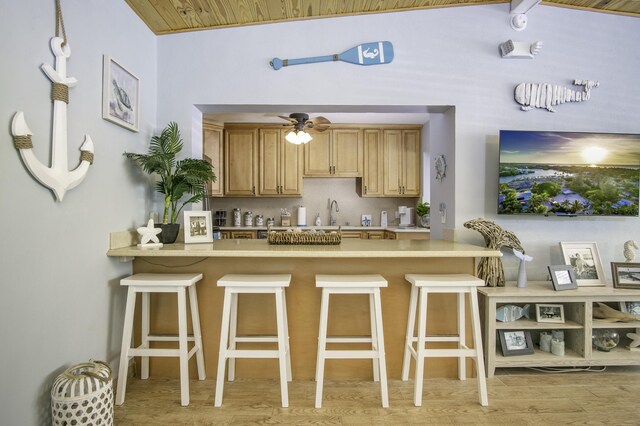 kitchen featuring ceiling fan, a kitchen breakfast bar, and light wood-type flooring