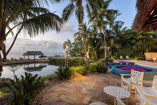 view of patio / terrace featuring a water view and a swimming pool with hot tub