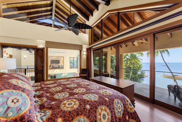 bedroom with a water view, wood-type flooring, high vaulted ceiling, beamed ceiling, and access to exterior