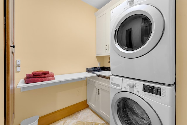 laundry area featuring cabinets and stacked washer / dryer