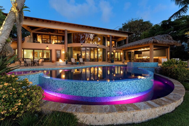 pool at dusk with a patio and an outdoor fire pit