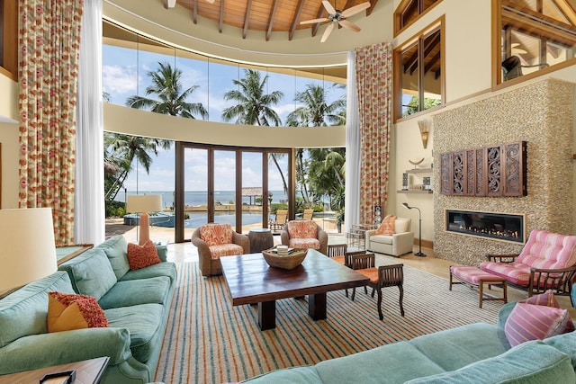 living room featuring beam ceiling, a water view, wood ceiling, a towering ceiling, and a premium fireplace