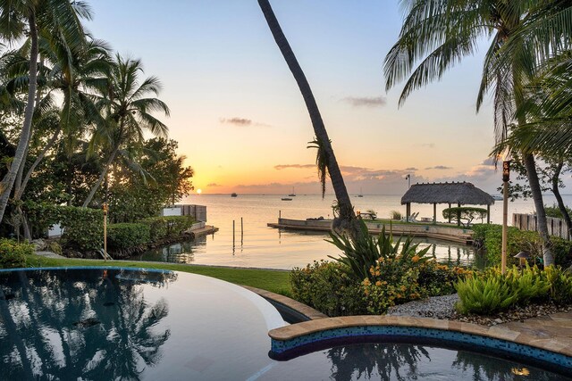 pool at dusk with a gazebo and a water view