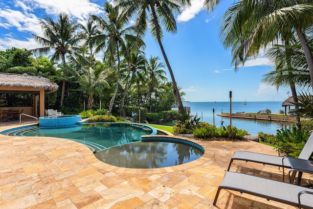 view of swimming pool with an in ground hot tub, a water view, and a patio area