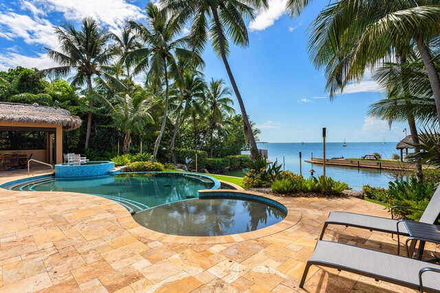 view of swimming pool with an in ground hot tub, a water view, and a patio area