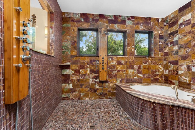 bathroom featuring shower with separate bathtub and tile walls