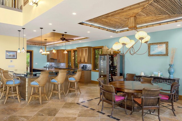 dining space with sink, a tray ceiling, wooden ceiling, and ceiling fan