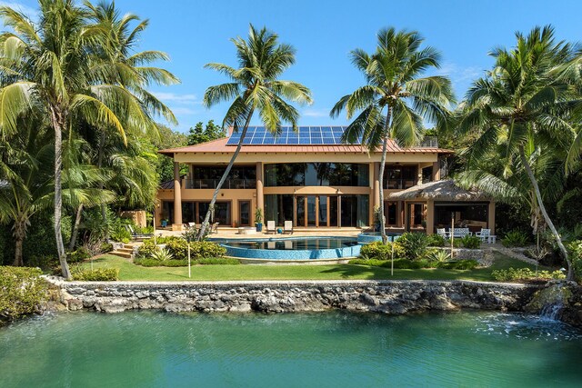 back of property with a yard, a gazebo, a patio, a water view, and solar panels