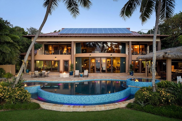 pool at dusk featuring an in ground hot tub and a patio