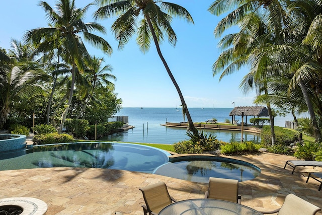 view of swimming pool with a patio, a water view, and an in ground hot tub