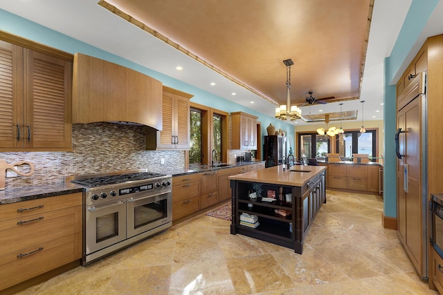 kitchen with decorative light fixtures, an island with sink, a chandelier, double oven range, and a raised ceiling