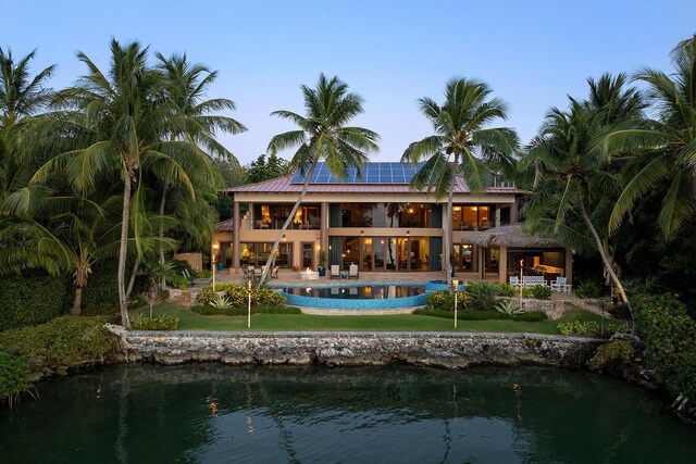 back of house featuring a patio, solar panels, and a water view