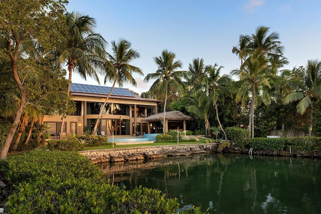 back of property featuring a balcony, a gazebo, a water view, and solar panels