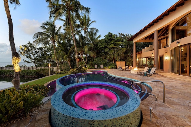 pool at dusk featuring an outdoor fire pit, a patio, and an in ground hot tub