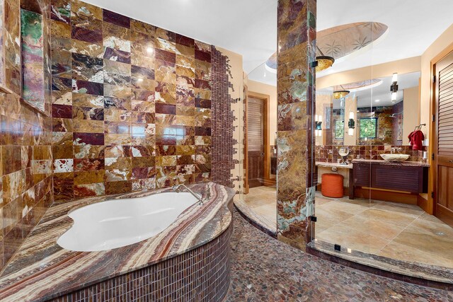 bathroom with vanity, tile walls, and tiled bath