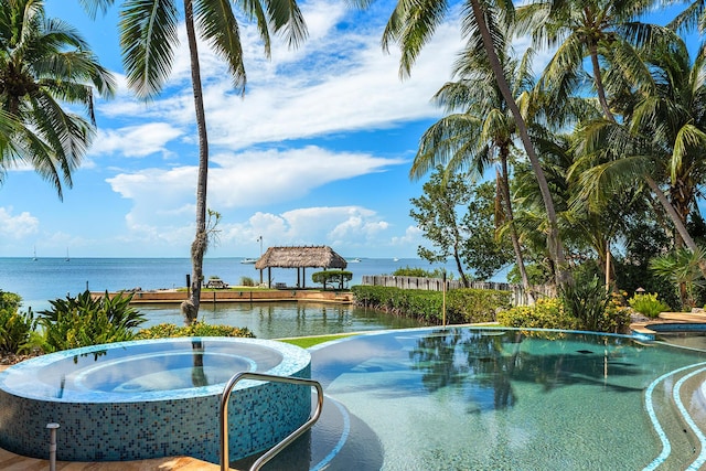 view of pool with an in ground hot tub and a water view