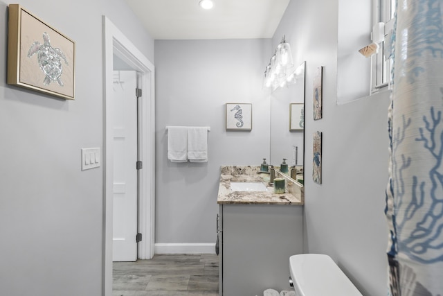 bathroom featuring toilet, wood finished floors, vanity, and baseboards