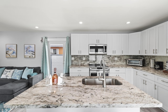 kitchen with white cabinetry, stainless steel appliances, and light stone counters