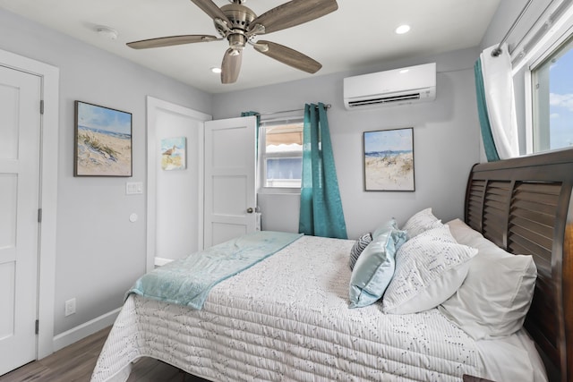 bedroom with ceiling fan, a wall unit AC, recessed lighting, wood finished floors, and baseboards