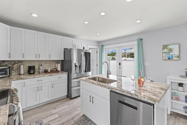 kitchen with a sink, white cabinetry, french doors, appliances with stainless steel finishes, and an island with sink