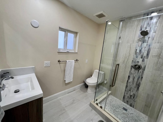 bathroom with vanity, a shower with door, and toilet