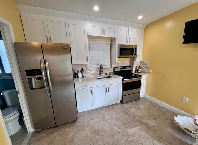 kitchen with appliances with stainless steel finishes, sink, decorative backsplash, and white cabinets