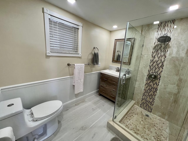 bathroom featuring vanity, wood-type flooring, toilet, and tiled shower