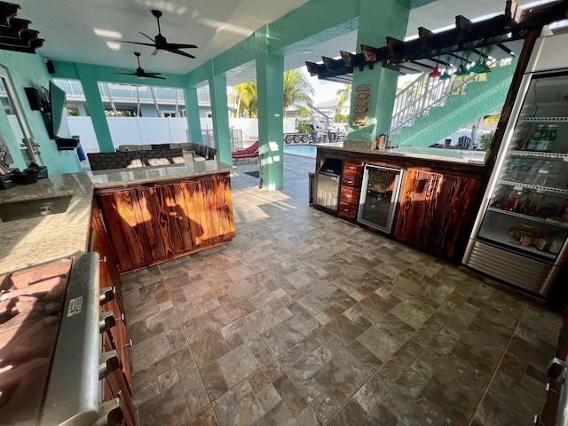 bar with light stone countertops and ceiling fan