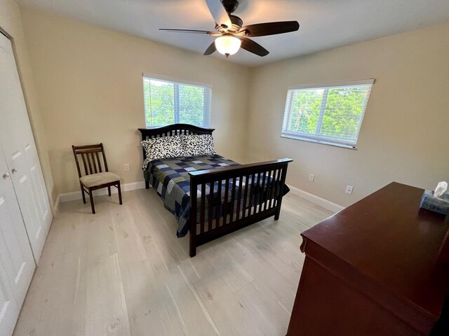 bedroom with ceiling fan, multiple windows, and light hardwood / wood-style flooring