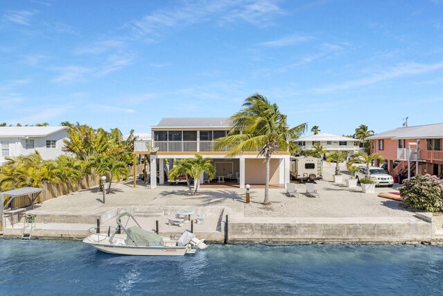 back of property with a sunroom, a patio, and a water view