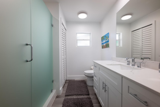 bathroom featuring vanity, hardwood / wood-style flooring, a shower with shower door, and toilet