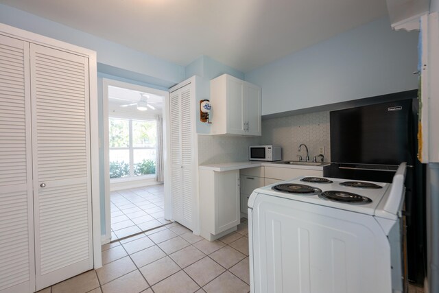 kitchen with white cabinetry, backsplash, white appliances, and light tile patterned flooring